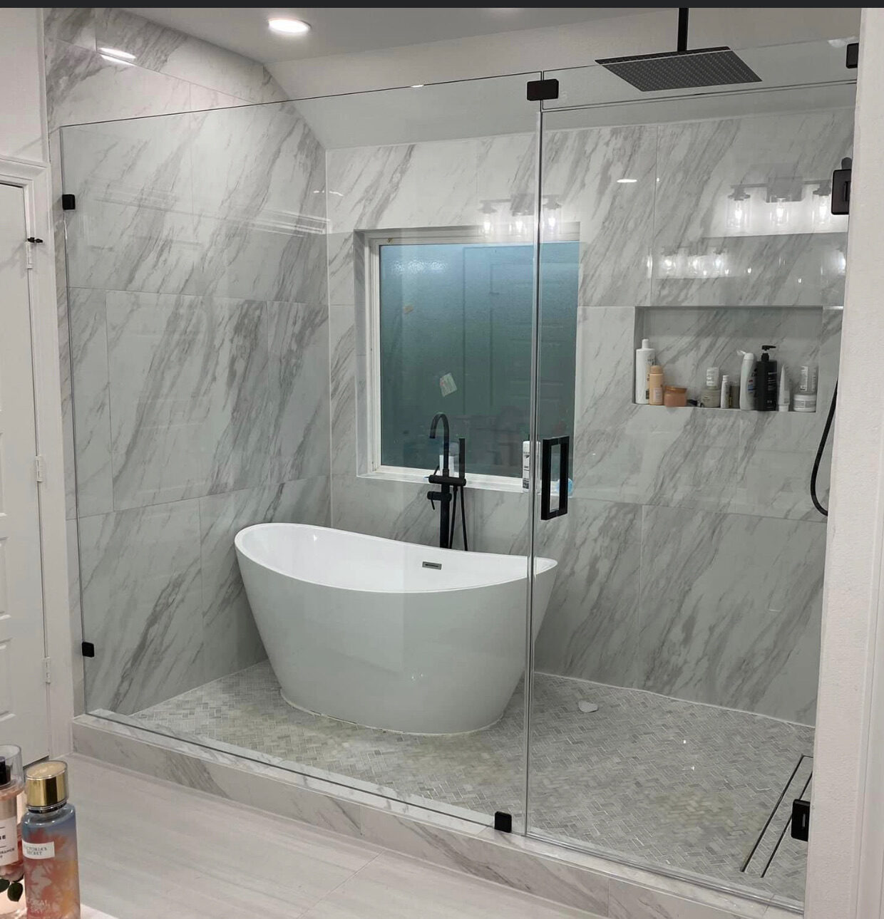 Frameless shower glass beside a freestanding tub